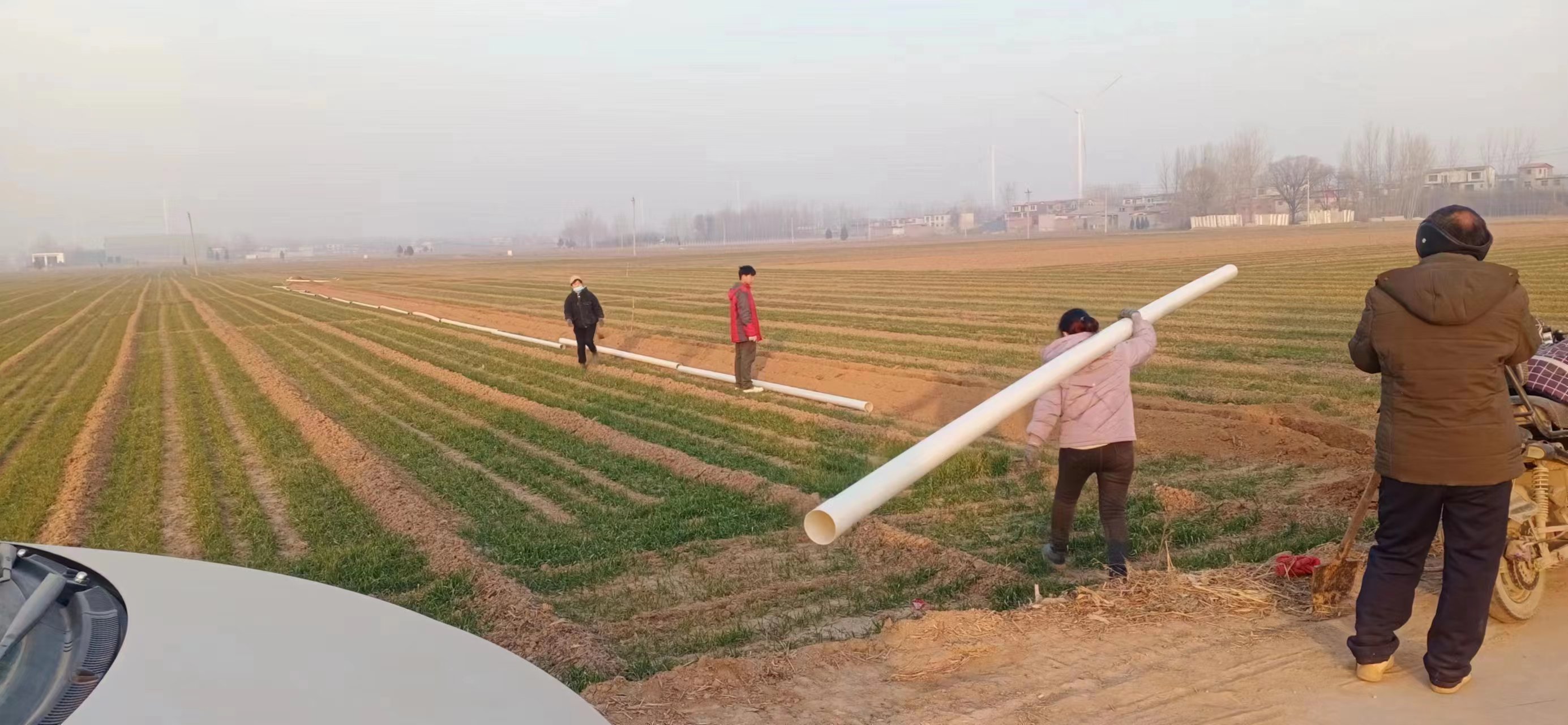 工人们正在田间地头铺设地埋管道,安装地埋管道出水口